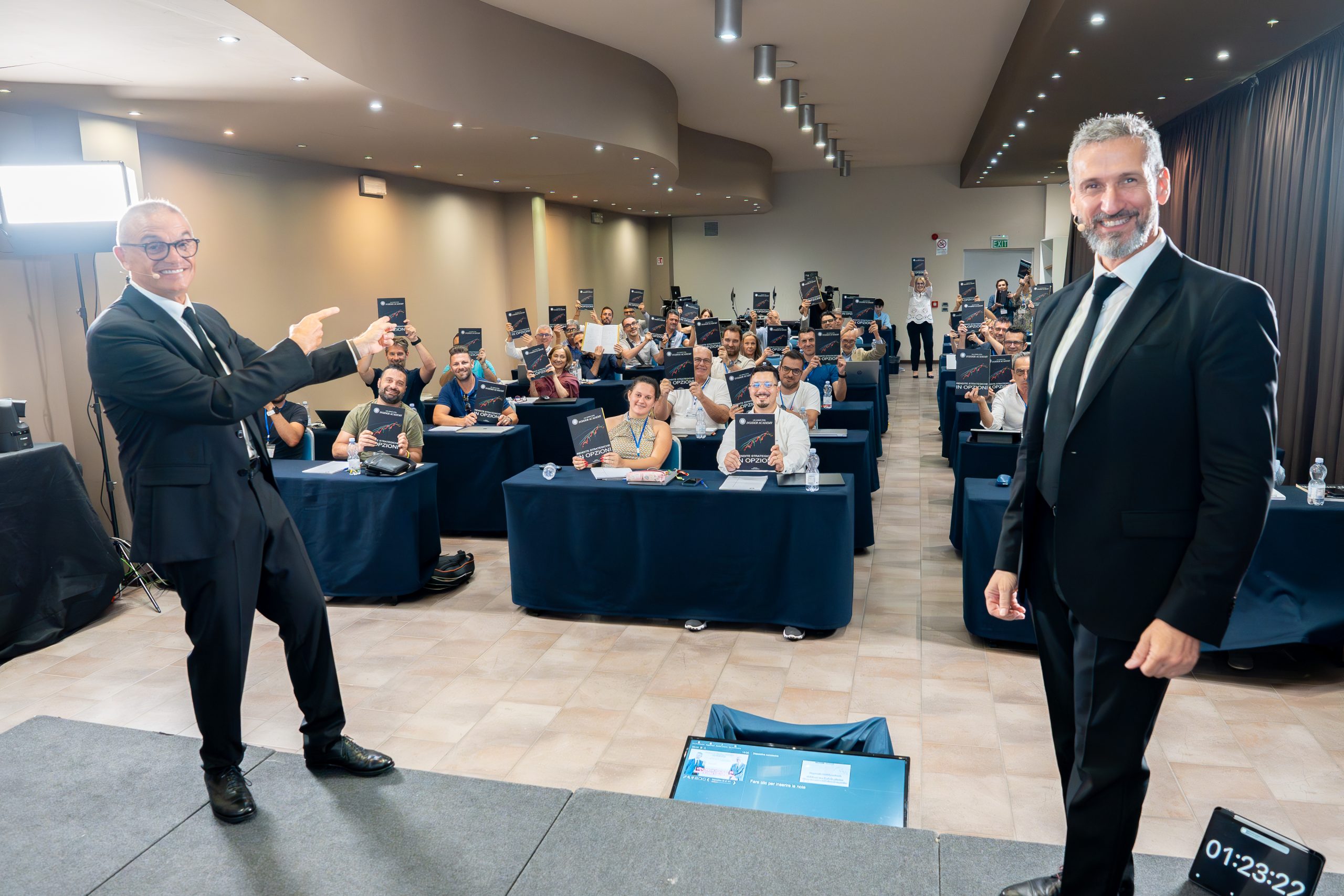 Aula Insider Academy: gli studenti mostrano il manuale di Opzioni, con i due docenti davanti al gruppo